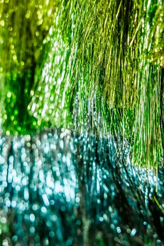 A close-up of a fringed jacket, lime-green strands falling into deep teal.